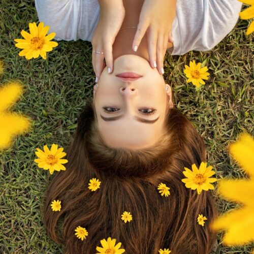 γυναικα ξαπλωμενη στο γρασιδι με κιτρινα λουλουδια